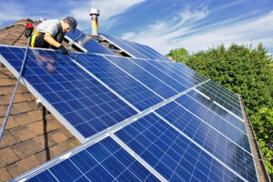 A worker installs solar panels on the roof of a home.
