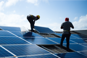 Two workers install solar panels on a residential roof.